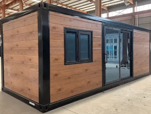 Wooden cabin with modern black framing and large glass doors inside an industrial warehouse